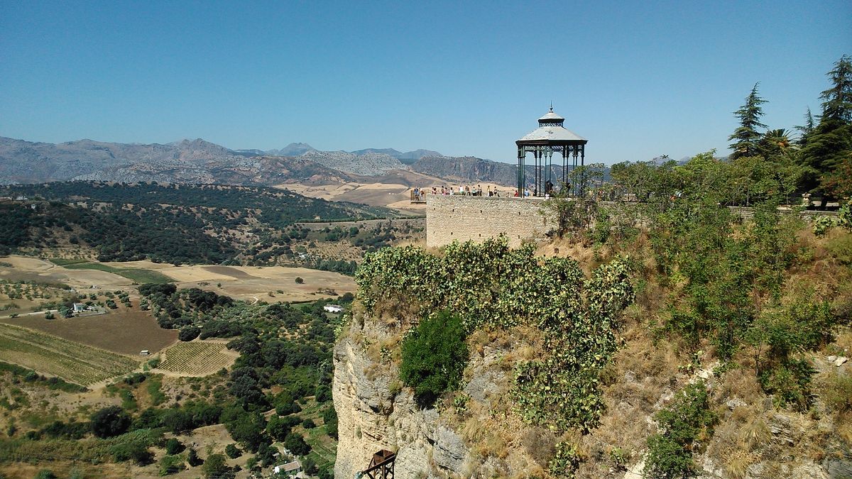 La ciudad se asienta sobre una meseta cortada por un profundo tajo excavado por el río Guadalevín. La imagen está tomada desde el parador de Ronda. Una imagen espectacular donde la gente que aparece en el mirador siente una completa fascinación y conectividad entre ellos y la naturaleza que se haya sobre sus pies.