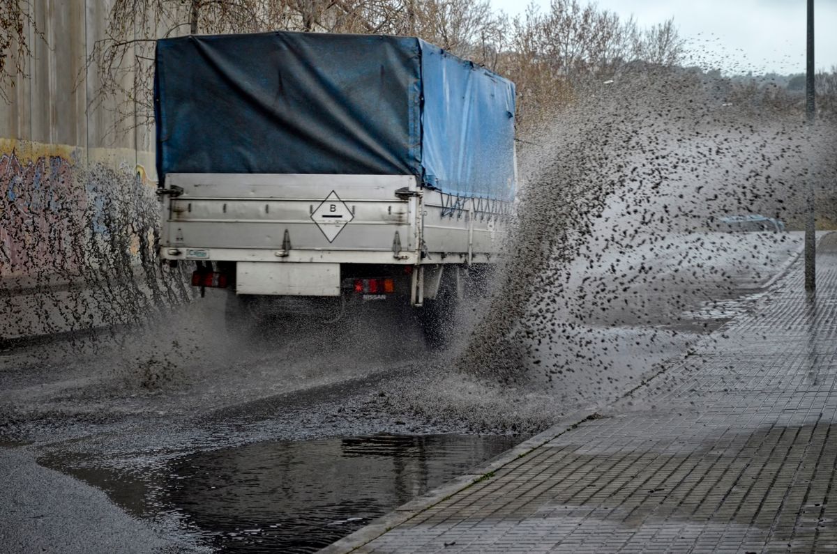 Camión salplicando el agua de la lluvia