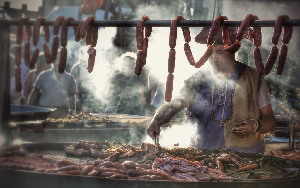 Cocinero en la calle , mientras la gente pasa entre el humo de la comida.