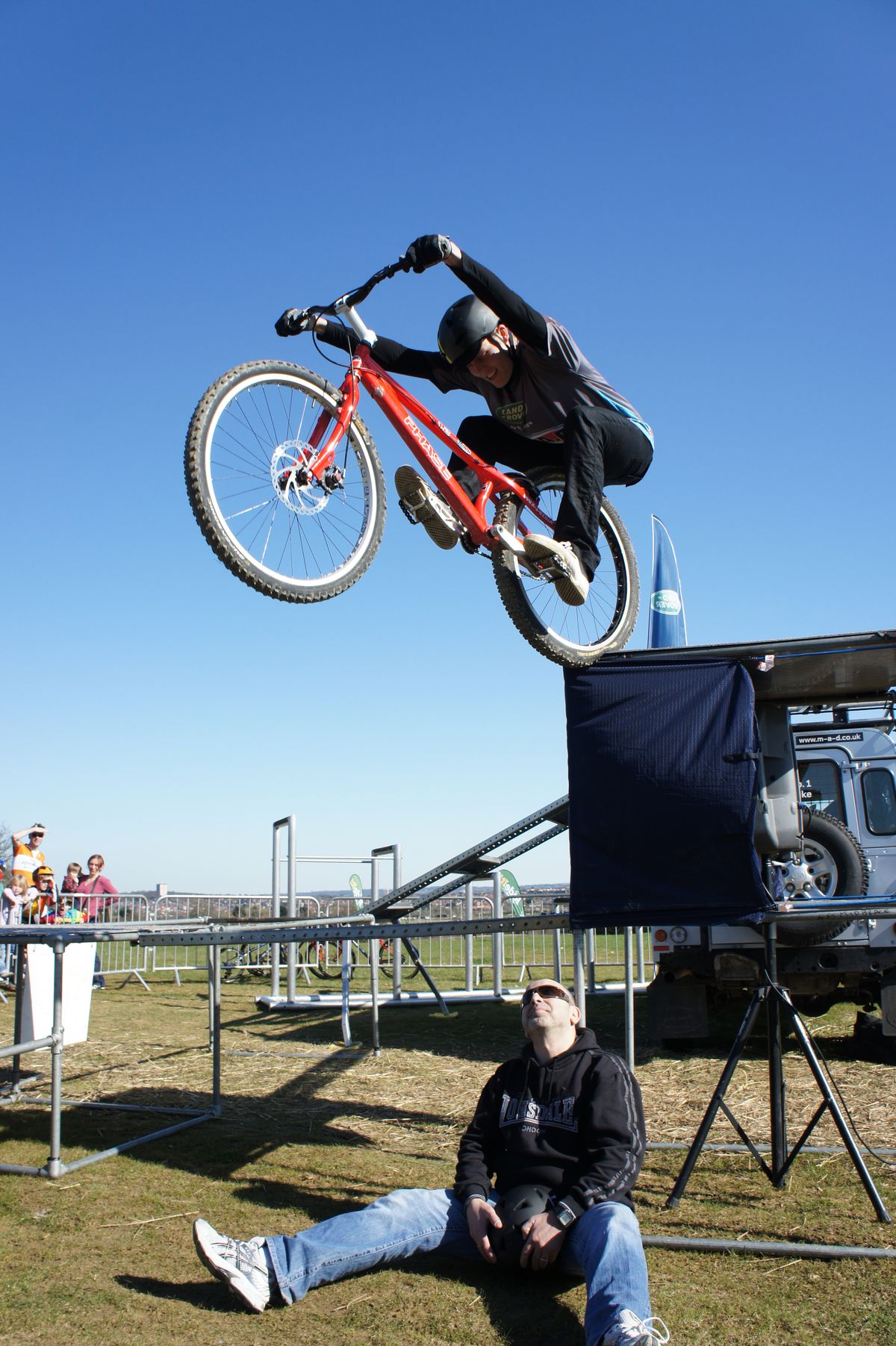 Stunt cyclists jump off the top of Landrovers over (mostly) willing volunteers from the crowd